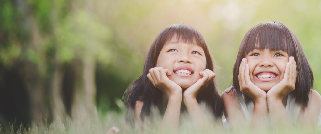 Two little girls looking into the sky.